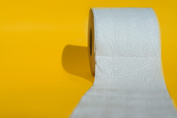 Rolls of new toilet paper lie on a yellow background