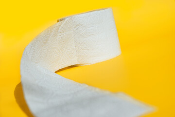 Rolls of new toilet paper lie on a yellow background