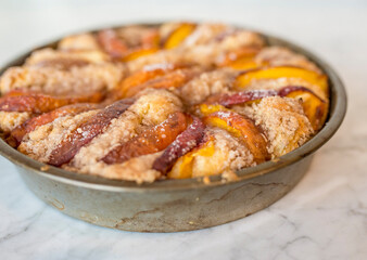 Homemade peach coffee cake with slices of colorful fruit arranged on top and sprinkled with coarse sugar.
