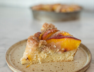 Slice of homemade peach coffee cake with slices of colorful fruit arranged on top and sprinkled with coarse sugar.  