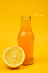 a bottle of aplexin juice with a small turbochka stands next to a lemon on a yellow background