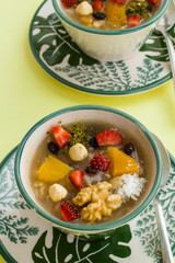 Traditional Turkish Dessert Ashura or Noah's Pudding in stylish green bowls on yellow background with hazelnuts.