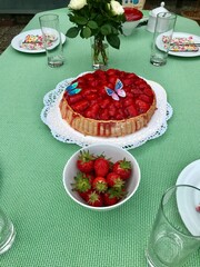 Freshly backed homemade strawberry cake with gelatin decorated with colorful butterflies sitting on a white table in the backyard looking delicious