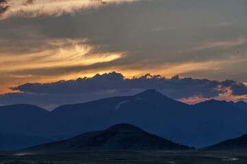 Naklejka na ściany i meble Mountain landscape at sunset. Outstanding view of the mountain ridges and clouds in Altai of Mongolia
