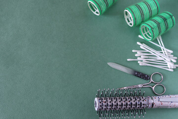 Hairdressing tools: plastic comb, hair curlers, cotton swabs, nail scissors and nail file on a green background with place for text. Women's beauty products - Powered by Adobe