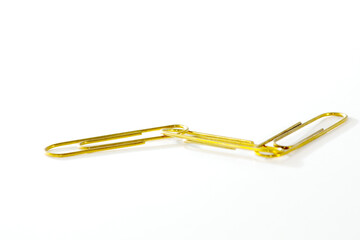 Gold paperclips linked against white background