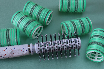 Hair brashing and green hair curlers on a green background. Close-up. The concept of creating a hairstyle.