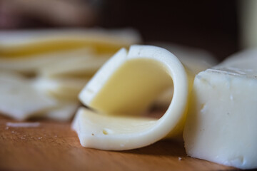 Chopped slices of cheese and next to it a piece of curled cheese
