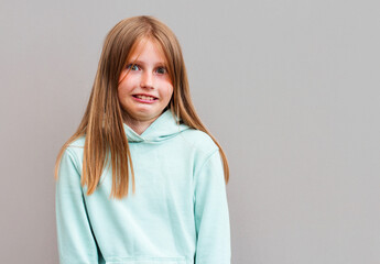 Fototapeta premium Studio shot of cute girl with blonde hair looking sideways with thoughtful and sly expression, raising one brow as if having good idea, planning something