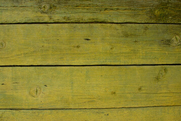 Old tumbledown weathered wood boards background with cracks, yellow painted, shabby rustic barn timbered siding aged withered faded flooring surface. Obsolete blank abstract rustic rundown wall.