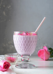 A glass of moon milk with a rose on a white table. Ayurvedic relaxing drink for the night.