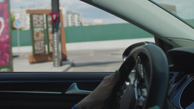 Female hands driving car in fast food restaurant. Ordering meal outdoors.