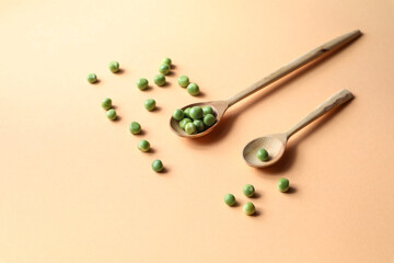 Green peas with wooden spoons on a yellow background, place for the inscription-the concept of eating healthy protein food