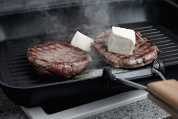 A large piece of fresh beef meat cooked in a grill pan. Meat is fried in butter. Stripes on the meat. Fluted frying pan.