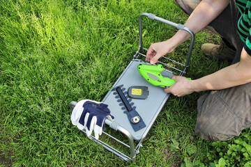 Hands gather and disassemble garden tools on a folding upside-down table. Changing cutting...