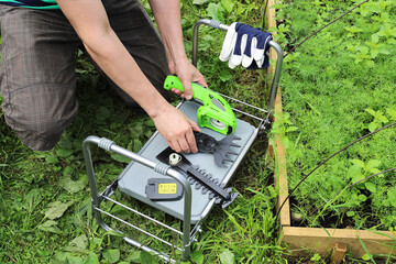 Hands gather and disassemble garden tools on a folding upside-down table. Changing cutting...