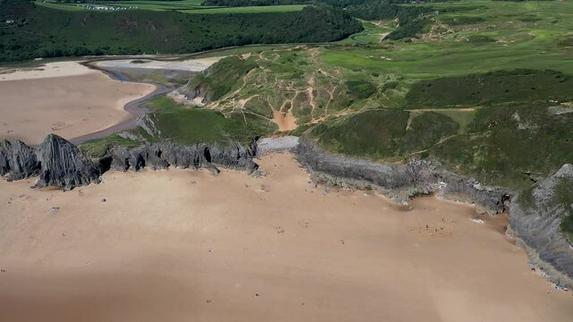 Aerial drone view flying along a huge sandy beach in a beautiful setting (3 Cliffs Bay and Pobbles, Gower Peninsula, Wales)