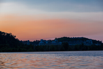 Naklejka premium Colorful sunset over the Sint Pietersberg (St Pieters mountain) and a silhouette of the former cement factory and skyline near Maastricht seen from the river Meuse. 