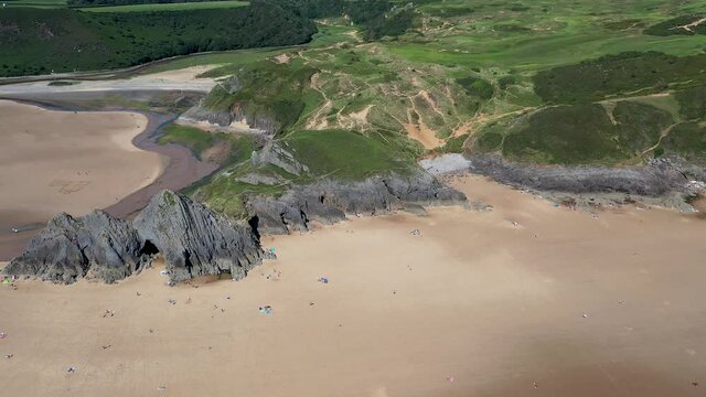 Aerial drone view flying along a huge sandy beach in a beautiful setting (3 Cliffs Bay and Pobbles, Gower Peninsula, Wales)