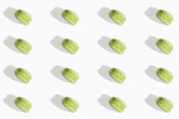 Top view of a pistachio and mint macarons pattern on white striped background.