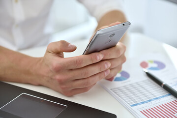 Businessman with mobile phone analyzing at graph and checking business plan.