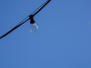 bulb of a black chain of lights in front of a blue sky