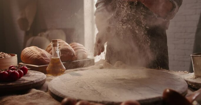 Experienced mature chef applying flour on hands before making traditional bread at bakery. Old man baking at home, enjoying hobby - closeup shot 4k footage