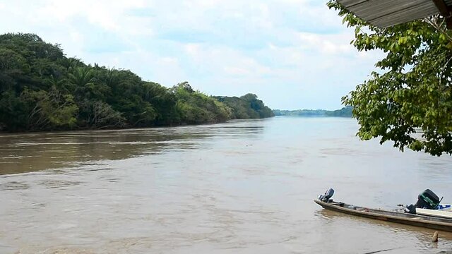 Scenic view of the Guayabero River and a green Amazonic Tropical Rainforest with a boat/canoe in the pier.