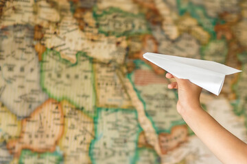 Fototapeta na wymiar Paper plane in hand on the background of the map. The map is blurred. Purpose. Dream to travel.