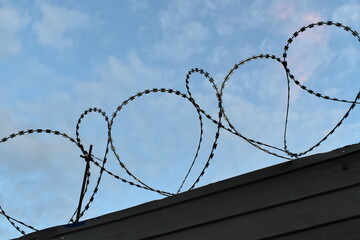 Barbed wire on the fence against the blue sky