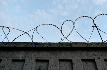 Protective barbed wire on the fence against the blue sky