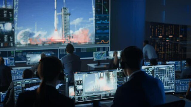 Group of People in Mission Control Center Witness Successful Space Rocket Launch. Flight Control Employees Sit in Front Computer Displays and Monitor the Crewed Mission. Team Stand Up and Clap Hands.