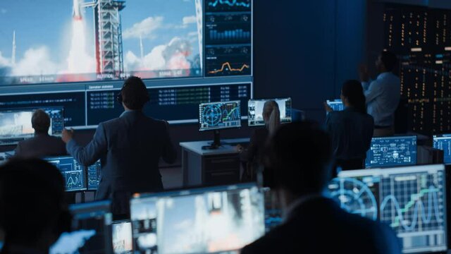Group of People in Mission Control Center Witness Successful Space Rocket Launch. Flight Control Employees Sit in Front Computer Displays and Monitor the Crewed Mission. Team Stand Up and Clap Hands.