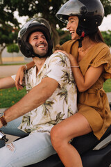 young couple of bikers closely looking at each other on black motorcycle on road