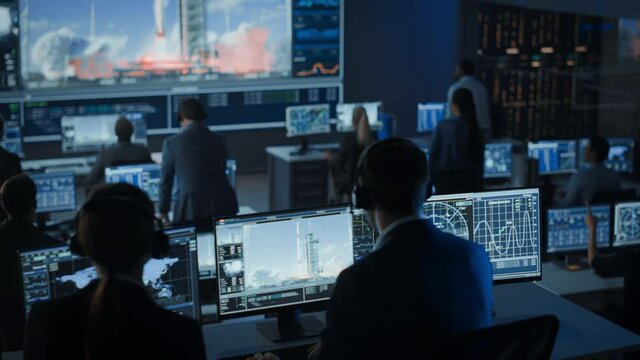 Group of People in Mission Control Center Witness Successful Space Rocket Launch. Flight Control Employees Sit in Front Computer Displays and Monitor the Crewed Mission. Team Stand Up and Clap Hands.