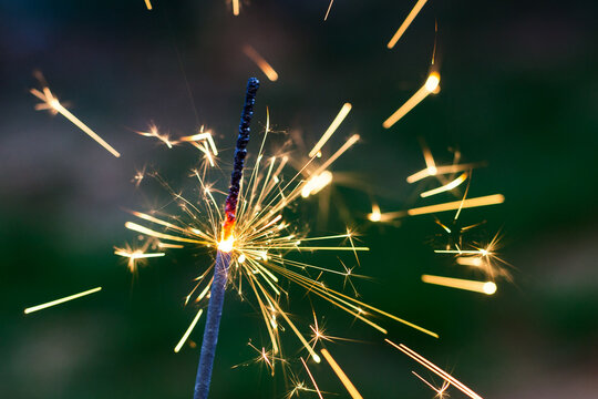 Palito de chispa encendido con fondo desenfocado en tonos verdes