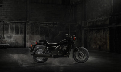 Fototapeta na wymiar Vintage motorcycle standing in a dark building in the rays of sunlight.