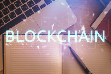 Fototapeta premium Blockchain theme hologram drawings over computer on the desktop background. Top view. Double exposure.