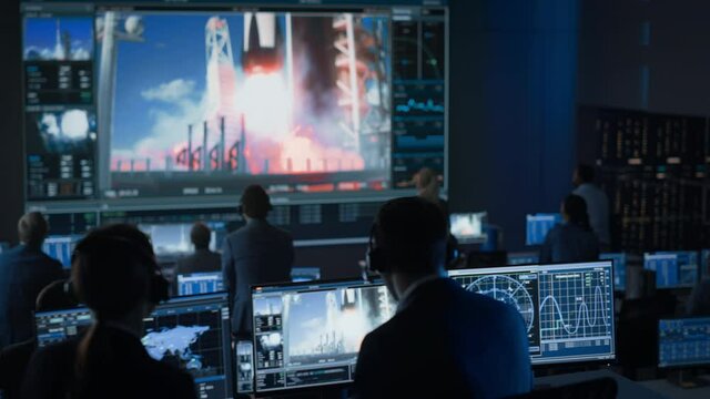 Group of People in Mission Control Center Witness Successful Space Rocket Launch. Flight Control Employees Sit in Front Computer Displays and Monitor the Crewed Mission. Team Stand Up and Clap Hands.