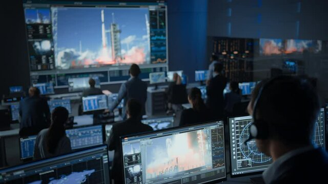Group of People in Mission Control Center Witness Successful Space Rocket Launch. Flight Control Employees Sit in Front Computer Displays and Monitor the Crewed Mission. Team Stand Up and Clap Hands.