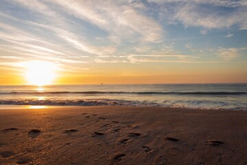 Fototapeta na wymiar sunrise on the beach with footprints in the sand