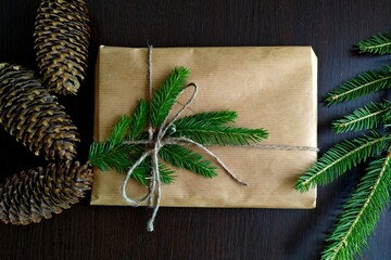 a christmas gift wrapped in craft paper and tied with linen thread with a mock-up surrounded by fir branches