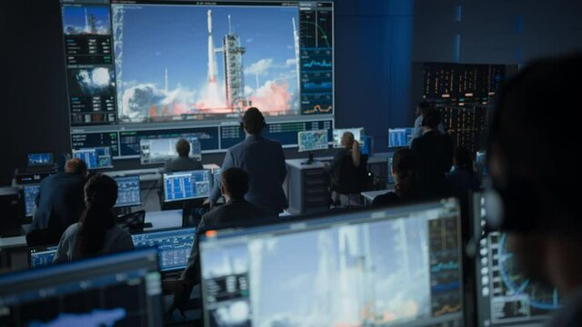 Group of People in Mission Control Center Witness Successful Space Rocket Launch. Flight Control Employees Sit in Front Computer Displays and Monitor the Crewed Mission. Team Stand Up and Clap Hands.