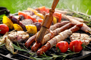 Grilled food, spreading aromatic marinade of bacon wrapped sausages close up view