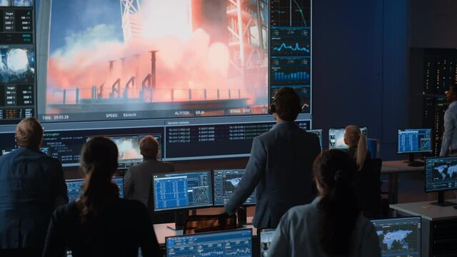 Group of People in Mission Control Center Witness Successful Space Rocket Launch. Flight Control Employees Sit in Front Computer Displays and Monitor the Crewed Mission. Team Stand Up and Clap Hands.