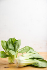 Fresh green bok choy or pac choi chinese cabbage on a brown wooden background. Side view, copy space.