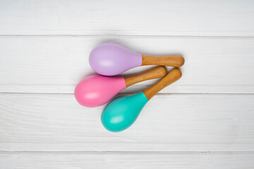 Children's wooden maracas are on a white table. Pink, lilac and mint maracas.