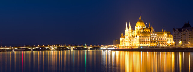Fototapeta na wymiar Panoramic view of Margaret bridge and Parliament building reflecting in water at night