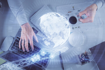 Multi exposure of man's hands typing over computer keyboard and world map hologram drawing. Top view. Technology concept.