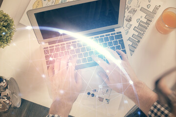 Double exposure of man's hands typing over computer keyboard and social network theme hologram drawing. Top view. People connection web concept.